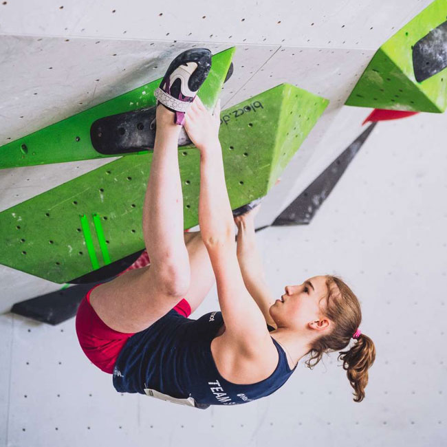 Athletin hängt athletisch an einem Boulder